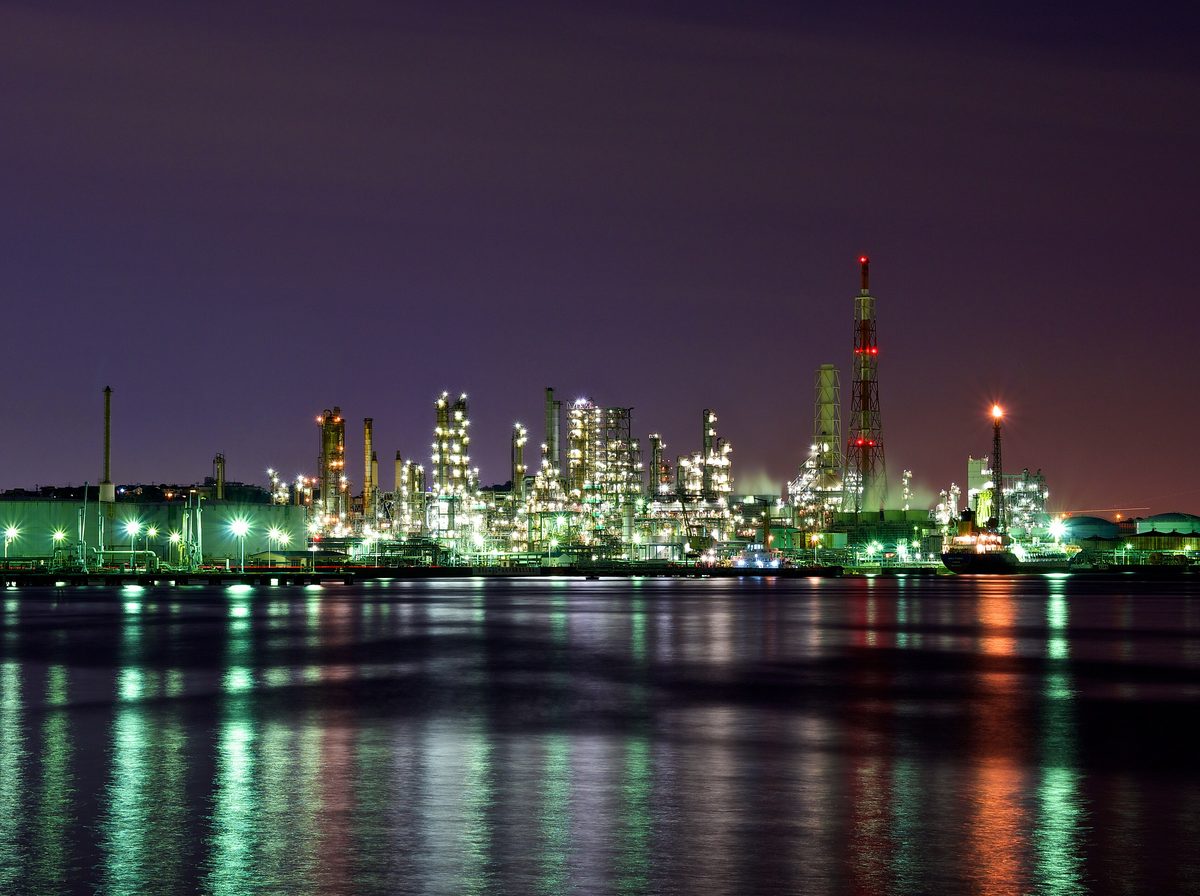 Refinery lit up at night, reflected in the water